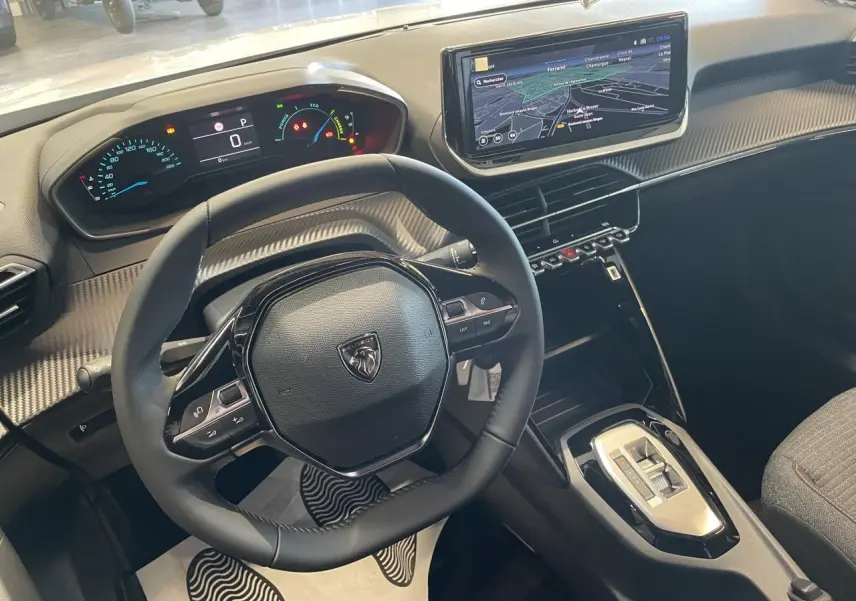Vue intérieure du poste de conduite du Peugeot 2008 blanc, avec volant compact, tableau de bord numérique et écran tactile 10 pouces.