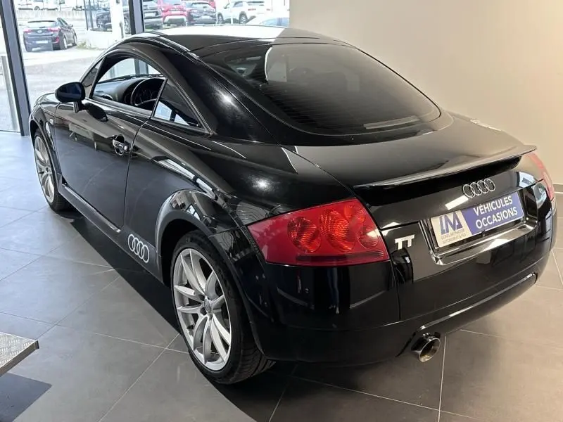 Audi TT Coupé noir de 2002 vu en 3/4 arrière droit, avec jantes argentées et logo Audi sur la porte.