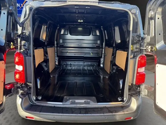 Vue arrière du Peugeot Expert Fourgon noir 2025 avec portes ouvertes montrant l'espace de chargement vide et les panneaux latéraux en bois.