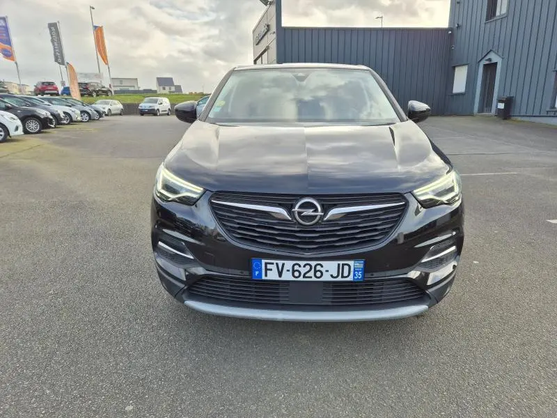 Vue frontale d'un Opel Grandland X noir diamant 2020 avec phares LED allumés sur parking extérieur.