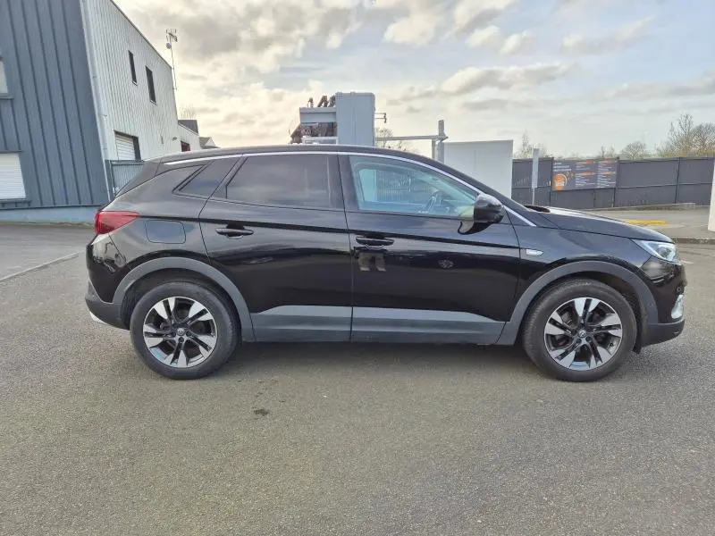 Vue de profil côté gauche d'un Opel Grandland X noir diamant avec jantes alliage et vitres arrière surteintées.