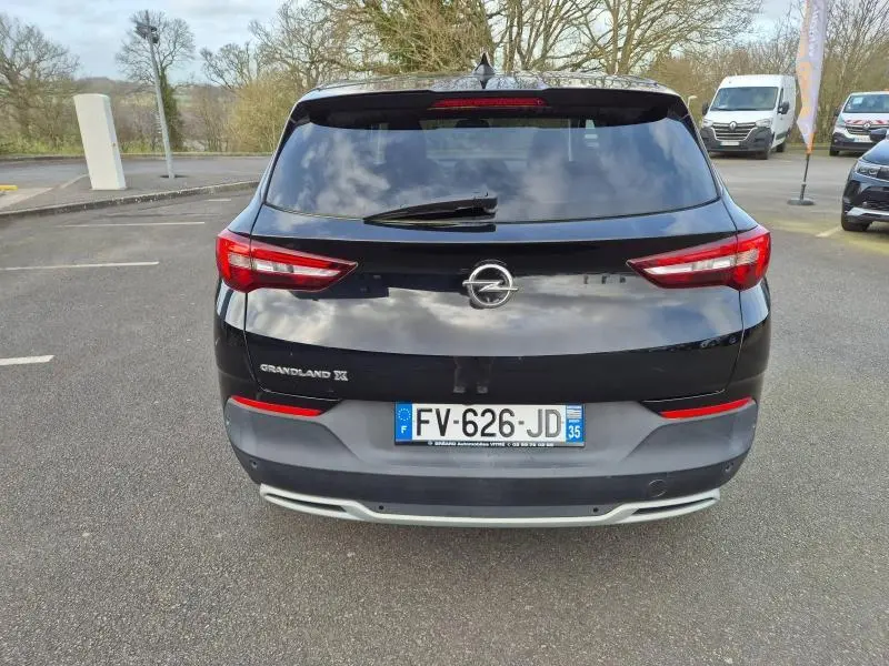 Vue arrière d'un Opel Grandland X noir diamant 2020 avec feux LED et lunette arrière surteintée sur parking.