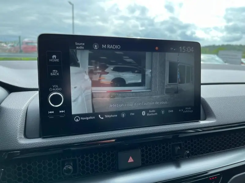 Écran tactile central du Honda CR-V 2024 affichant la caméra de recul avec vue arrière sur un véhicule blanc.