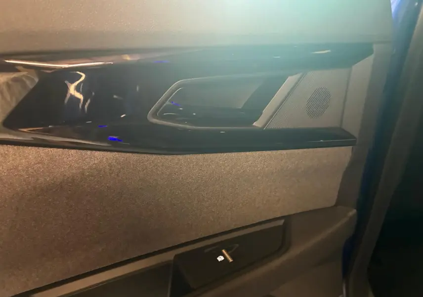 Gros plan sur la poignée intérieure et la commande de vitre côté gauche d’une Renault Austral bleu, finition tissu gris-noir.