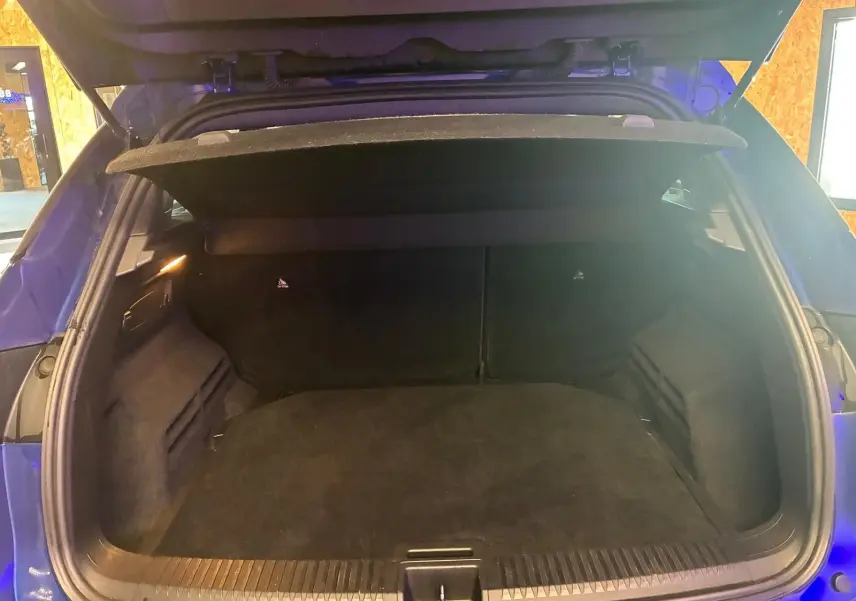 Coffre ouvert vu de l'arrière d'un Renault Austral bleu, montrant un espace de chargement vide et propre.