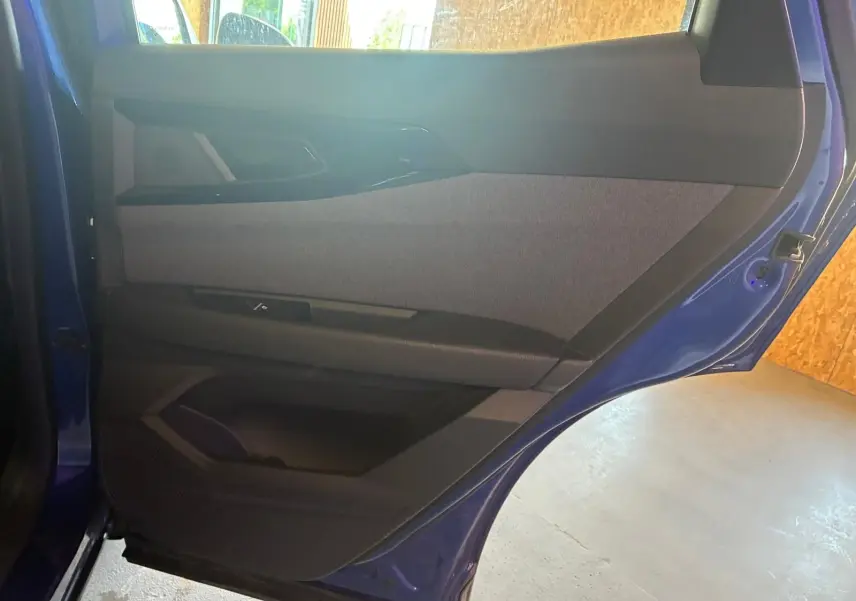 Vue intérieure de la porte arrière droite bleu du Renault Austral 2024, avec garniture tissu gris et éléments noirs.