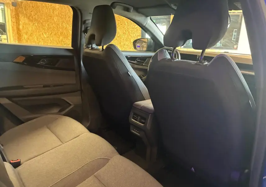 Vue intérieure arrière côté gauche du Renault Austral 2024, sièges tissu gris-noir et console centrale avec aérateurs.
