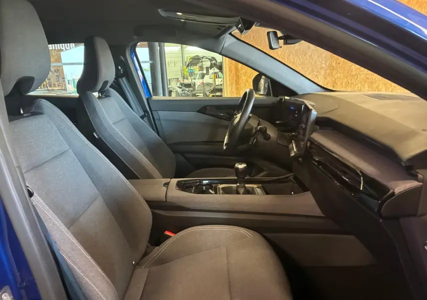 Vue intérieure côté gauche du Renault Austral bleu 2024, montrant les sièges tissu gris et la console avec boîte manuelle.