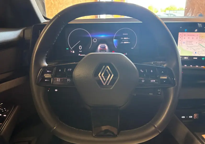 Vue intérieure centrée sur le volant noir de la Renault Austral 2024 avec tableau de bord numérique et écran tactile.