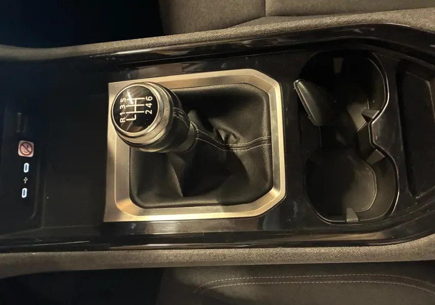 Gros plan sur le levier de vitesse manuel entouré de cuir noir et console centrale brillante dans un Renault Austral bleu 2024.