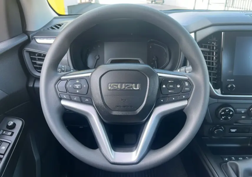 Vue centrée sur le volant multifonctions noir de l'Isuzu D-MAX 2026 avec tableau de bord et écran tactile à droite.