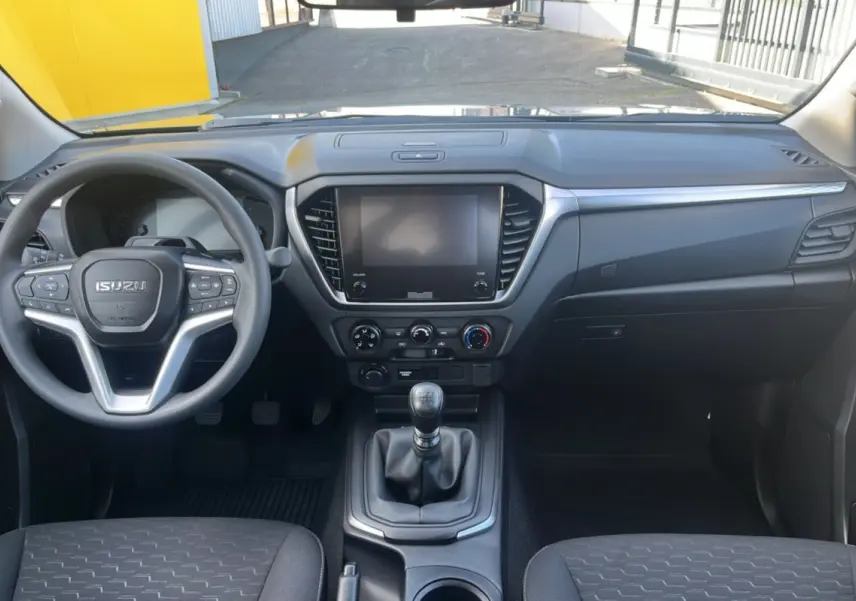 Vue intérieure avant de l'Isuzu D-MAX 2.2 TD 164 Space Evolution avec tableau de bord noir et volant multifonctions.