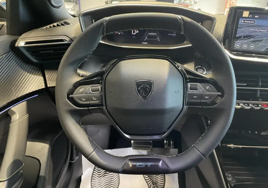 Vue centrée sur le volant GT noir du Peugeot 2008 hybride 2026 avec tableau de bord numérique et écran tactile.