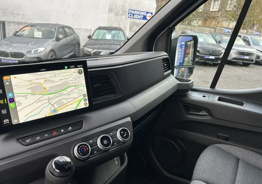 Vue intérieure côté passager du tableau de bord du Renault Master blanc, avec écran tactile et commandes climatisation visibles.