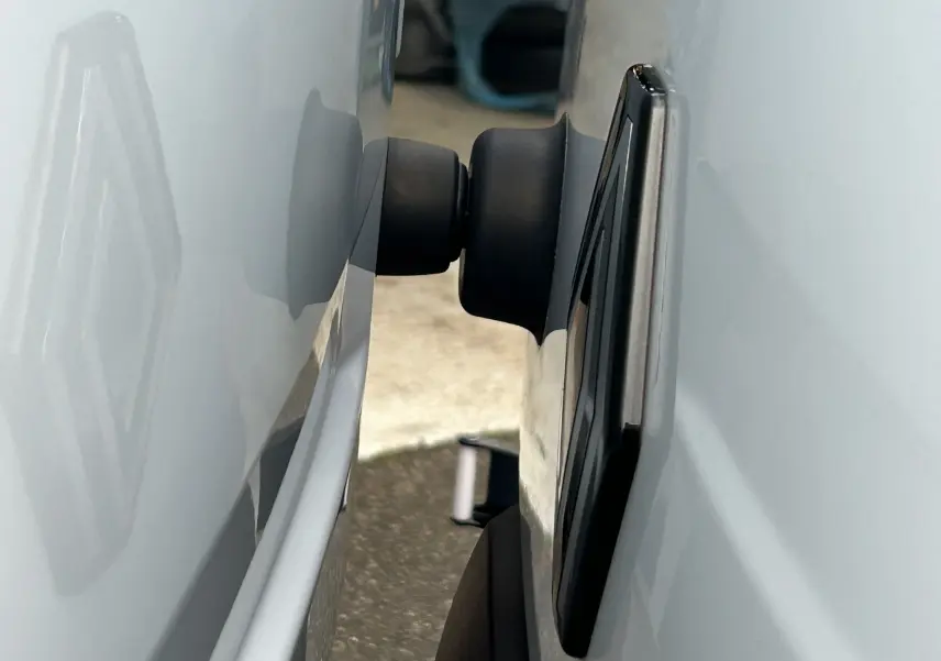 Gros plan sur la fixation noire entre la porte et la carrosserie blanche d’un Renault Master Fourgon.