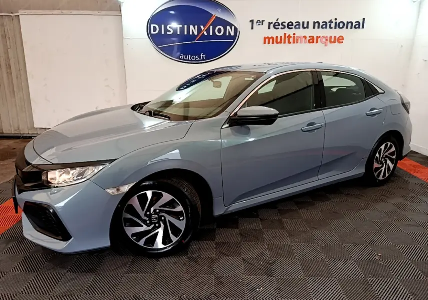 Honda Civic 1.0 i-VTEC Exclusive gris clair vue 3/4 avant droit en intérieur showroom avec jantes bicolores.