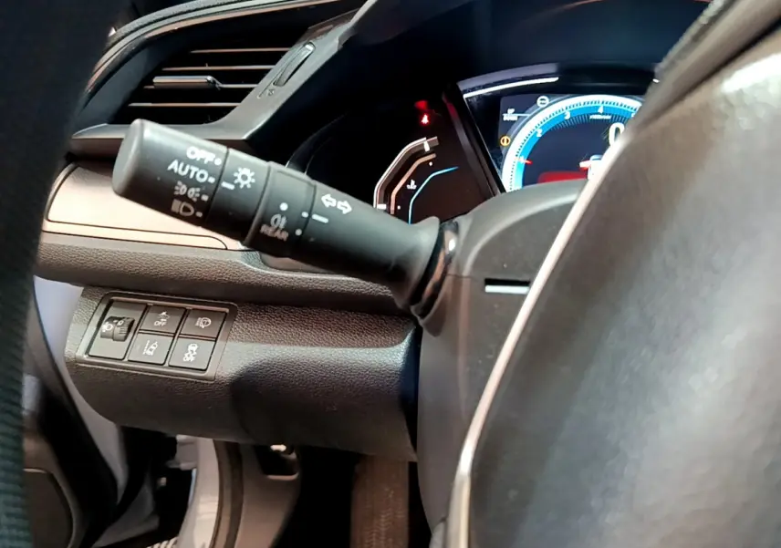 Gros plan sur la manette d'éclairage et le tableau de bord numérique de la Honda Civic 1.0 i-VTEC Exclusive 2020.