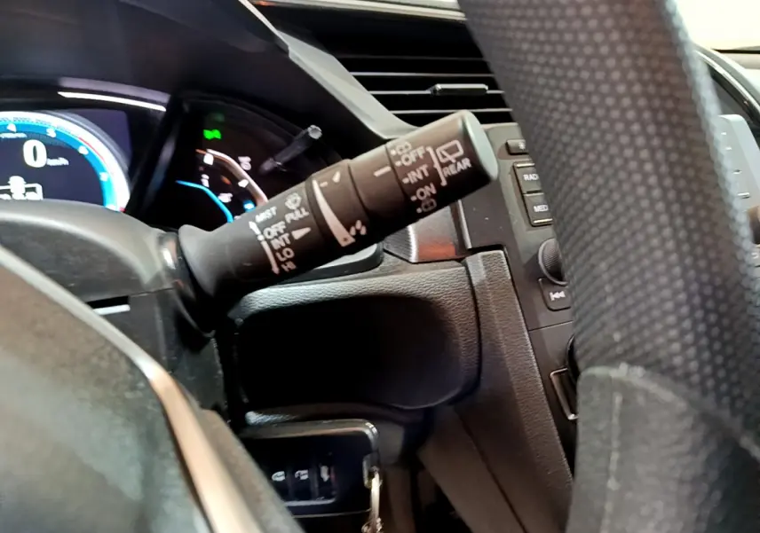 Gros plan sur la manette d'essuie-glace à gauche du volant en cuir dans l'habitacle sombre de la Honda Civic 2020.