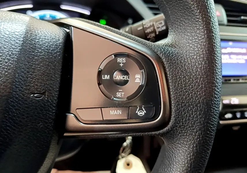Gros plan sur les commandes du régulateur adaptatif au volant cuir d'une Honda Civic 1.0 i-VTEC Exclusive 2020.