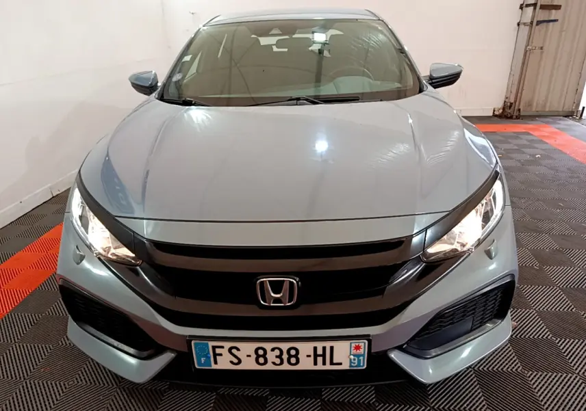 Vue avant d'une Honda Civic 1.0 i-VTEC Exclusive gris foncé, phares allumés dans un garage.