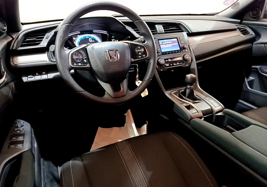 Intérieur noir de la Honda Civic 1.0 i-VTEC 2020, vue depuis le siège conducteur sur le volant et la console centrale avec boîte manuelle.