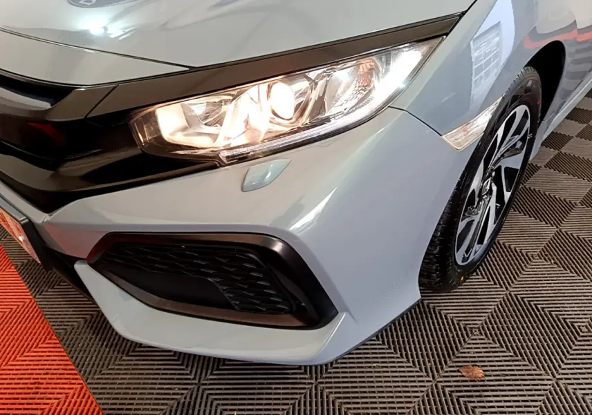 Gros plan sur l'avant droit gris clair de la Honda Civic 1.0 i-VTEC avec phare allumé et jante alliage noire.