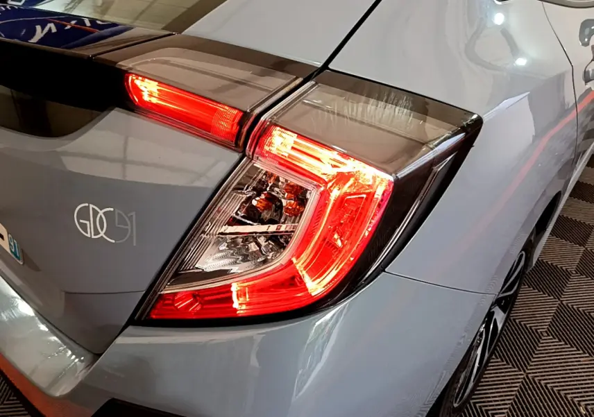 Gros plan sur le feu arrière droit rouge d'une Honda Civic gris foncé 2020, avec partie de la carrosserie visible.