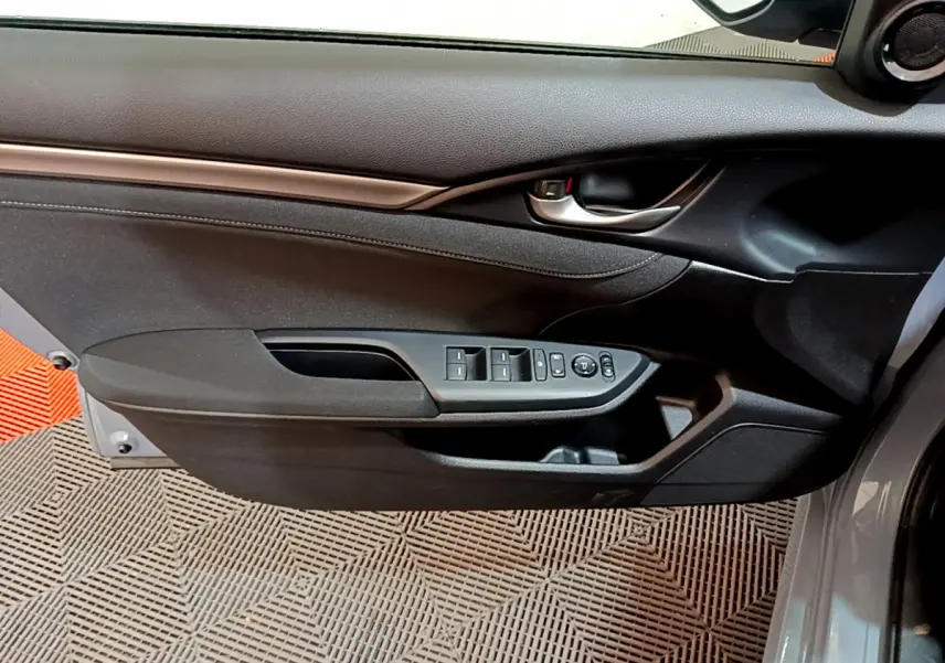 Vue rapprochée de la porte avant gauche grise de la Honda Civic 1.0 i-VTEC avec commandes électriques des vitres et rétroviseurs.