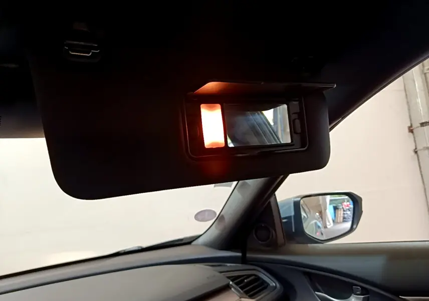 Vue intérieure côté conducteur de la Honda Civic gris foncé 2020, avec pare-soleil et miroir éclairé visible.