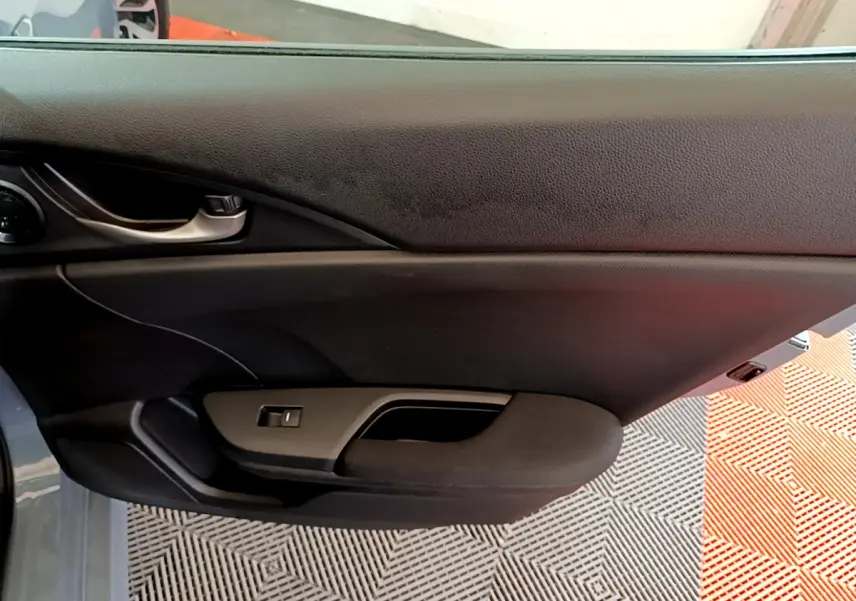 Gros plan sur la porte côté gauche de la Honda Civic 1.0 i-VTEC Exclusive gris foncé avec poignée intérieure noire.