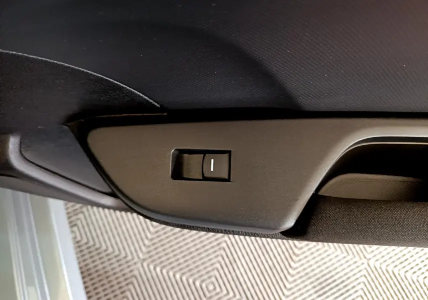 Détail du bouton d'ouverture du toit ouvrant sur la garniture intérieure noire d'une Honda Civic gris foncé.