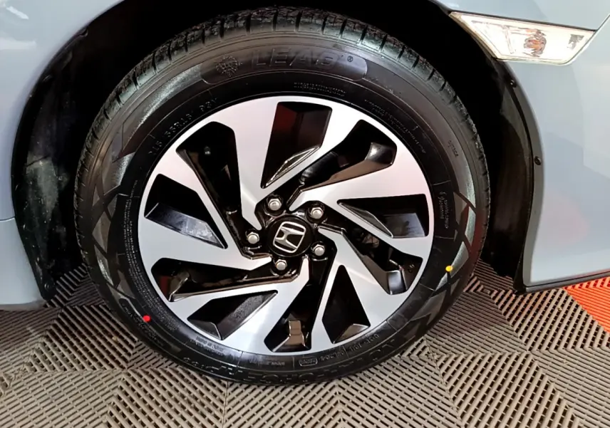 Gros plan sur la roue avant gauche d'une Honda Civic 1.0 i-VTEC Exclusive gris foncé avec jante alliage noire et argentée.