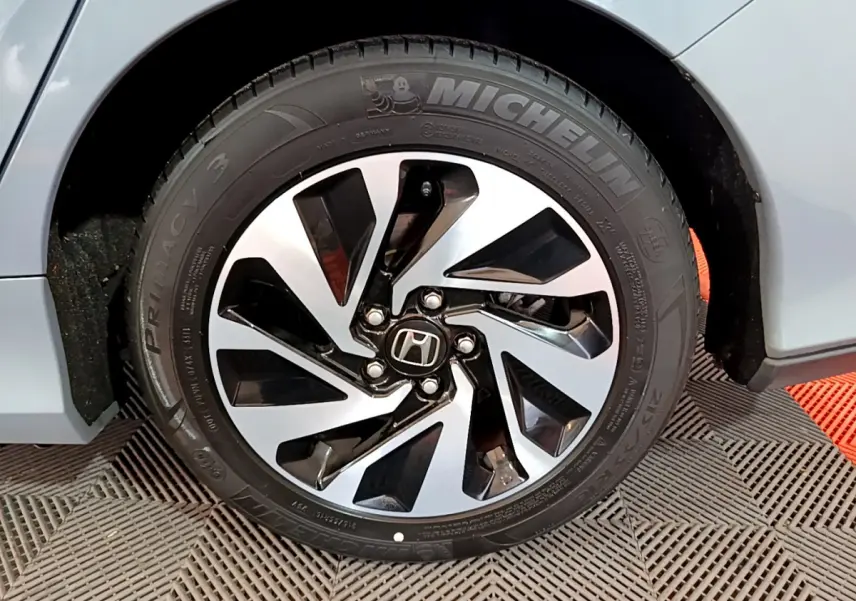 Gros plan sur la roue avant droite gris foncé de la Honda Civic 1.0 i-VTEC Exclusive avec jante au design moderne noir et argent.