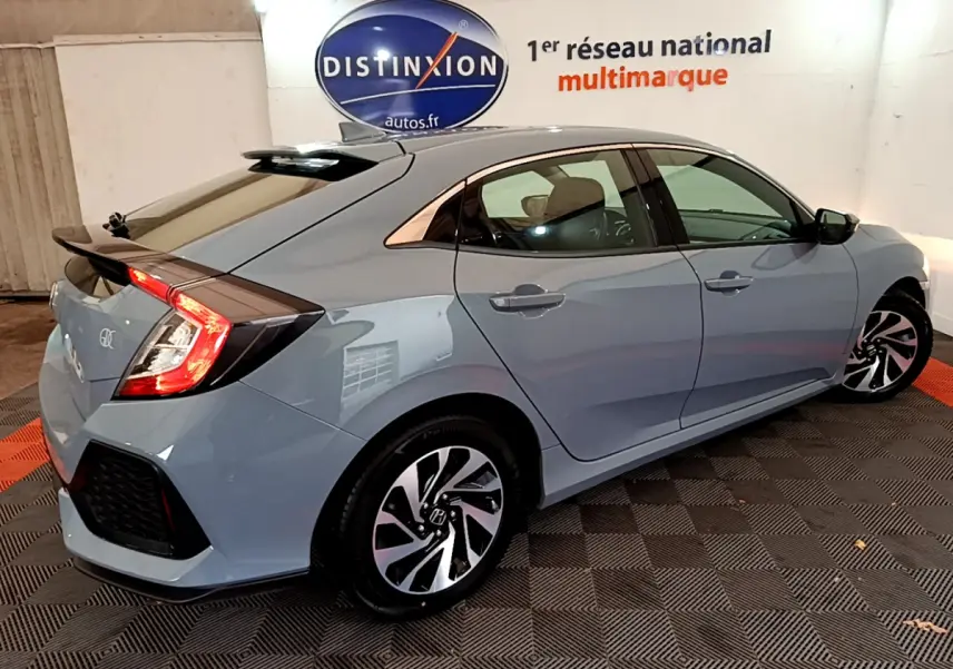 Vue 3/4 arrière droite d'une Honda Civic 1.0 i-VTEC Exclusive gris foncé avec feux arrière allumés et jantes stylisées.