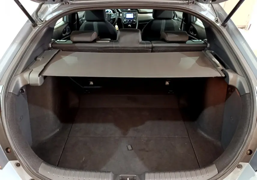 Vue arrière du coffre ouvert d'une Honda Civic gris foncé 2020, avec tablette cache-bagages et sièges arrière visibles.