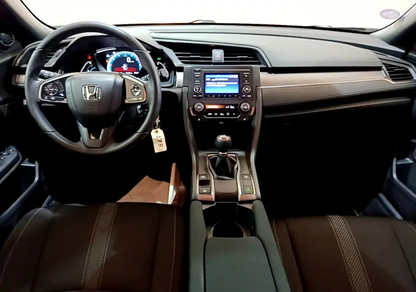 Intérieur avant de la Honda Civic 1.0 i-VTEC Exclusive 2020, tableau de bord noir avec volant cuir et boîte manuelle.