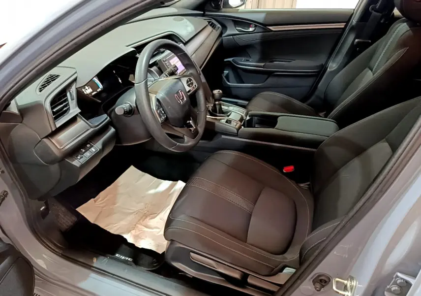 Vue intérieure côté conducteur de la Honda Civic 1.0 i-VTEC Exclusive 2020 avec sièges noirs et tableau de bord moderne.