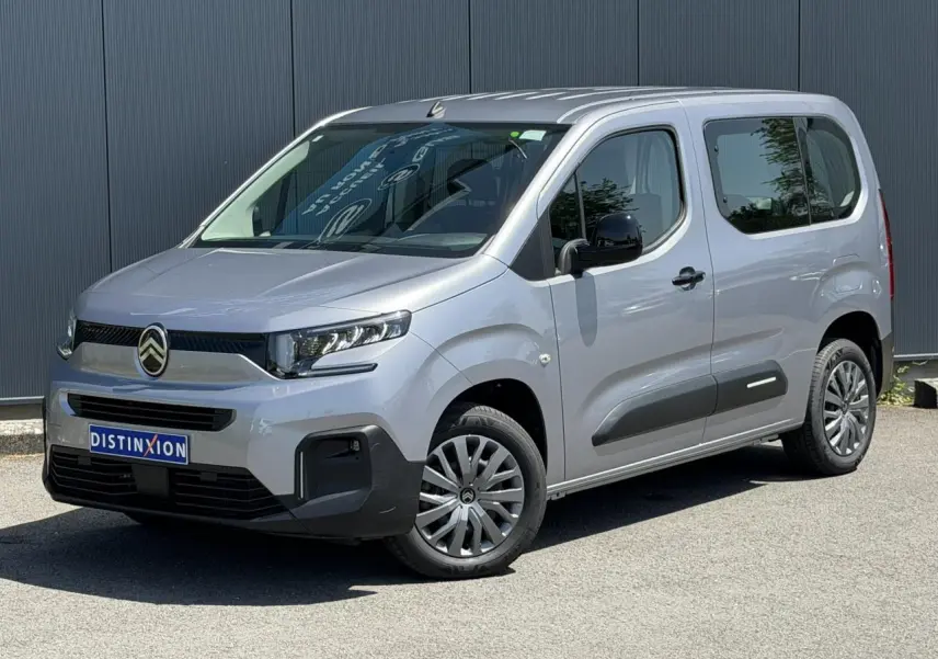Citroën Berlingo ë-136 gris Artense en 3/4 avant droit, avec jantes tôles et protections latérales noires.