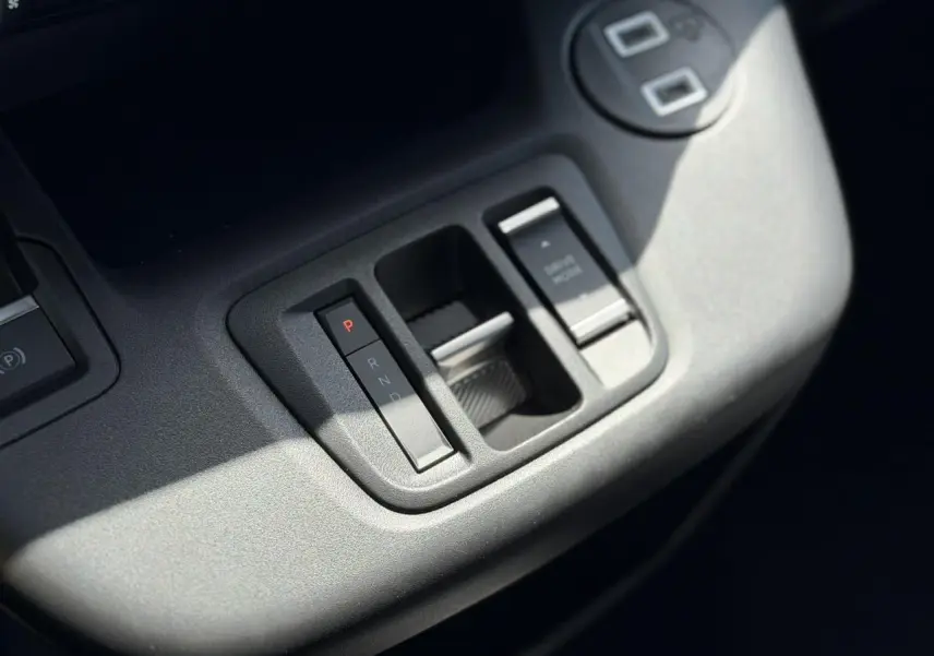 Gros plan sur la console centrale grise du Citroën Berlingo ë-136 avec commandes de boîte automatique et frein de stationnement.