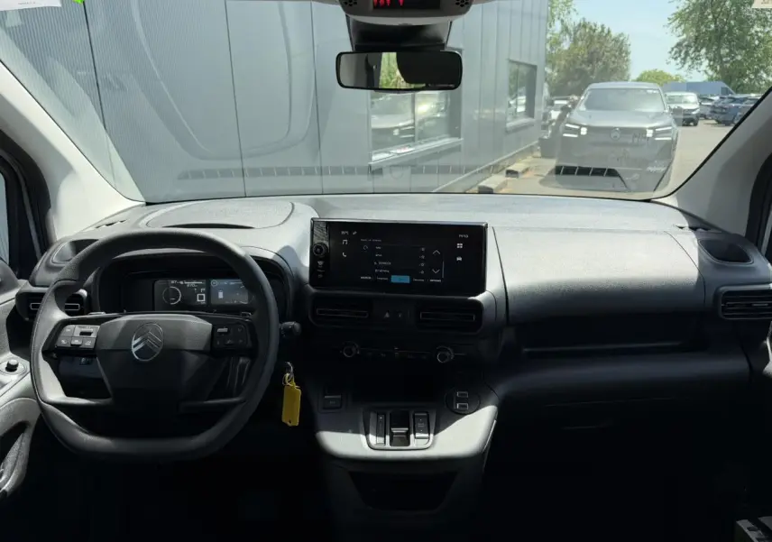 Vue intérieure avant du Citroën Berlingo ë-136 gris Artense, avec tableau de bord et écran tactile central.