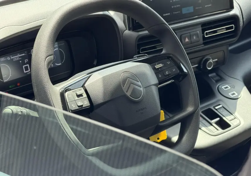 Vue rapprochée du volant multifonction et du tableau de bord numérique du Citroën Berlingo ë-136 gris Artense.
