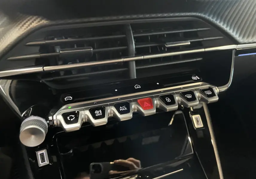 Détail de la console centrale noire brillante du Peugeot 2008 bleu, avec commandes climatisation et prise USB type C.