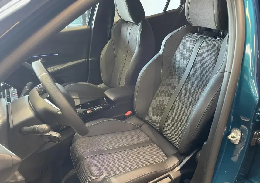 Vue intérieure côté conducteur du Peugeot 2008 bleu, montrant les sièges en tissu et cuir avec surpiqûres contrastées.