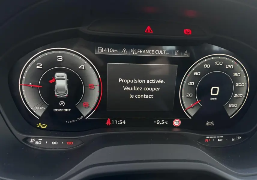 Vue rapprochée du tableau de bord numérique de l'Audi Q2 30 TDI S-Line 2025 affichant la vitesse, le régime moteur et un message d'alerte.