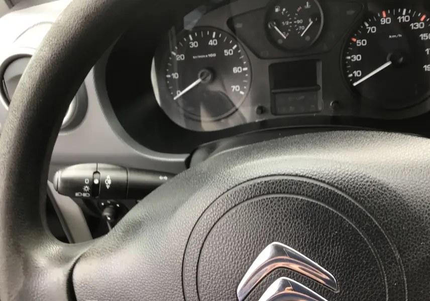 Vue rapprochée du volant noir et du tableau de bord du Citroën Berlingo blanc, version 2019 diesel.