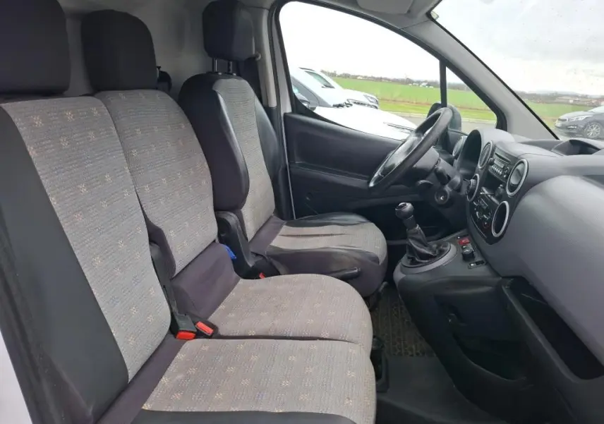 Vue intérieure côté conducteur du Citroën Berlingo blanc 2019, montrant les sièges tissu gris et la console avec boîte manuelle.