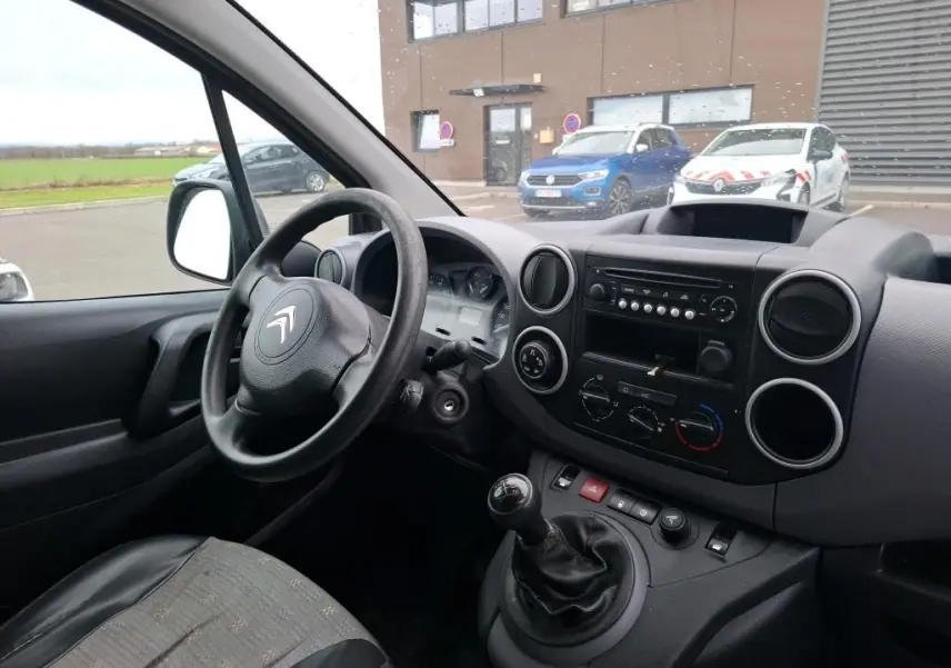 Vue intérieure côté conducteur du Citroën Berlingo blanc 2019, montrant volant, tableau de bord et levier de vitesses manuel.