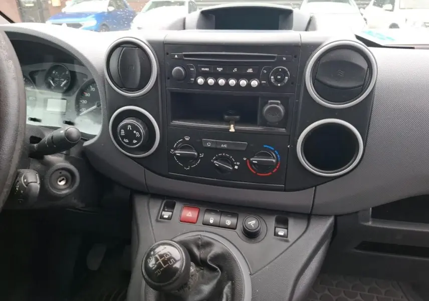 Vue intérieure du tableau de bord d'un Citroën Berlingo blanc 2019, avec boîte manuelle et commandes de climatisation visibles.