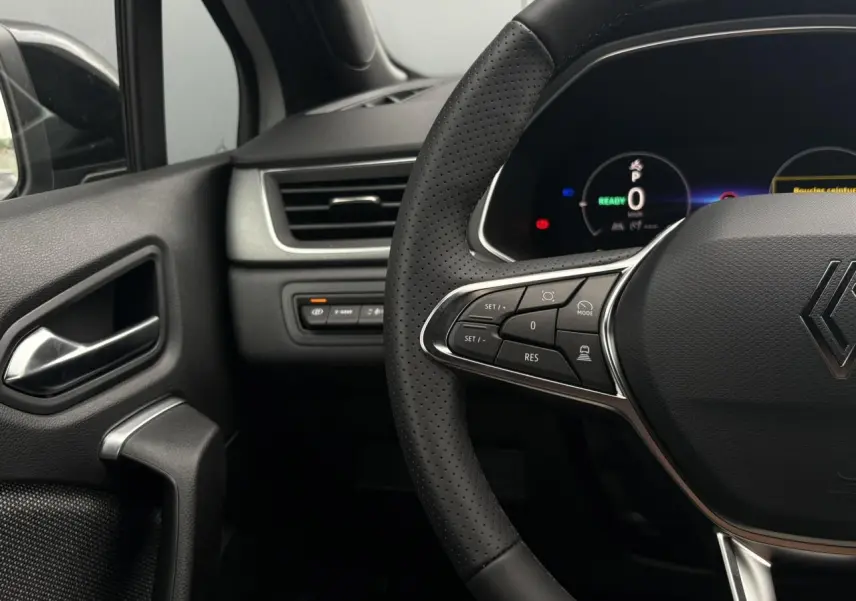 Gros plan sur le volant noir perforé et le tableau de bord numérique du Renault Captur, côté gauche intérieur.