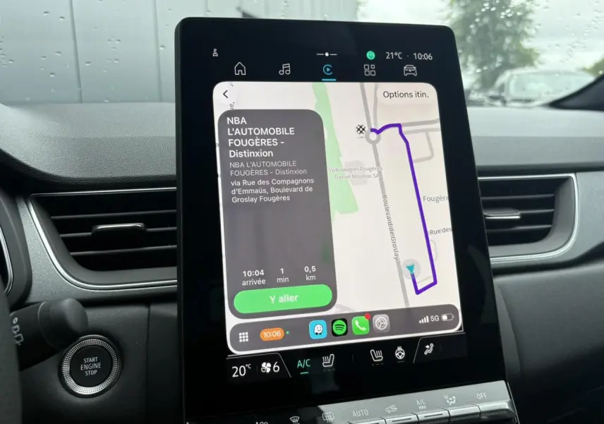 Écran tactile central du Renault Captur blanc nacré, vue intérieure montrant la navigation GPS et commandes climatisation.